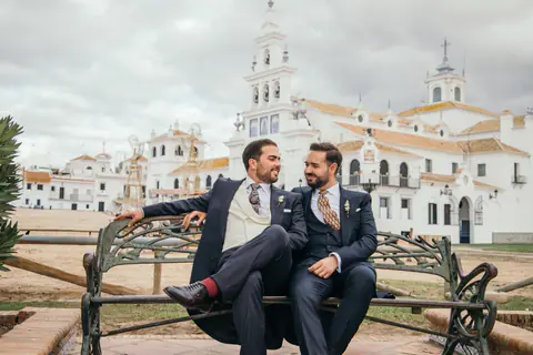 Los novios sentados en un banco de forja frente a la ermita de El Rocío, en Almonte (Huelva)